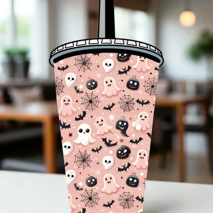 A Halloween-themed cup with a pink background and various ghost and spider motifs, including bats, skulls, and pumpkins.
