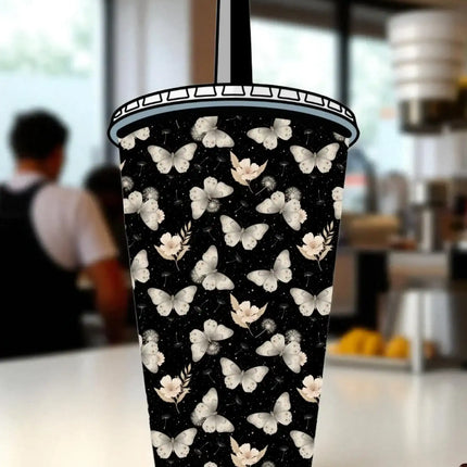 A black and white patterned cup with a butterfly design on it, placed on a table.