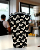 A black and white patterned cup with a butterfly design on it, placed on a table.