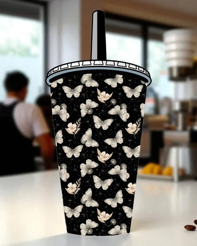 A black and white patterned cup with a butterfly design on it, placed on a table.