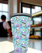 A colorful, patterned beverage cup with various Christmas-themed illustrations and text, including the words 